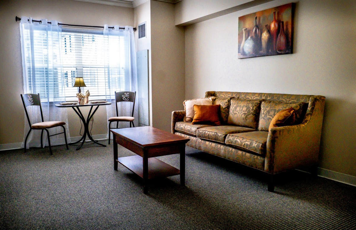 A cozy living room with a sofa, coffee table, and a small dining area by the window.