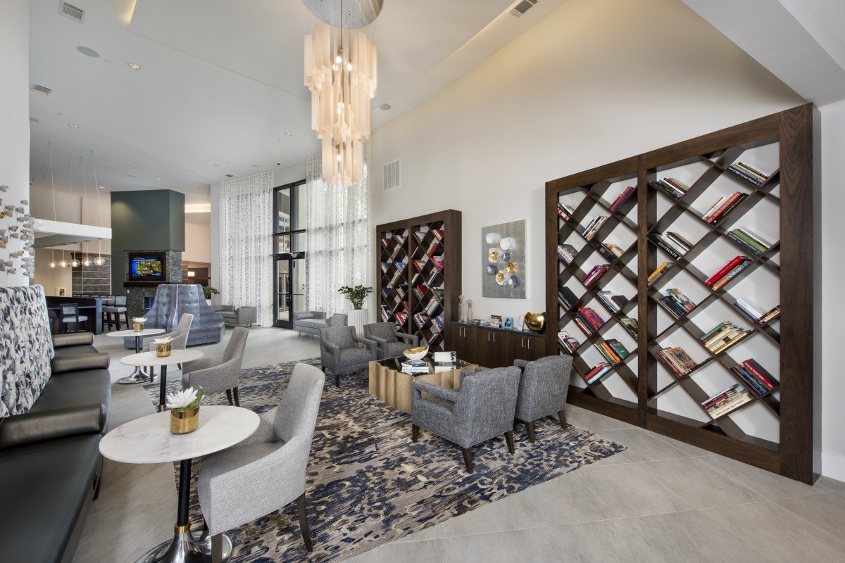 A modern lounge area featuring comfortable seating, wine racks, and a stylish chandelier.