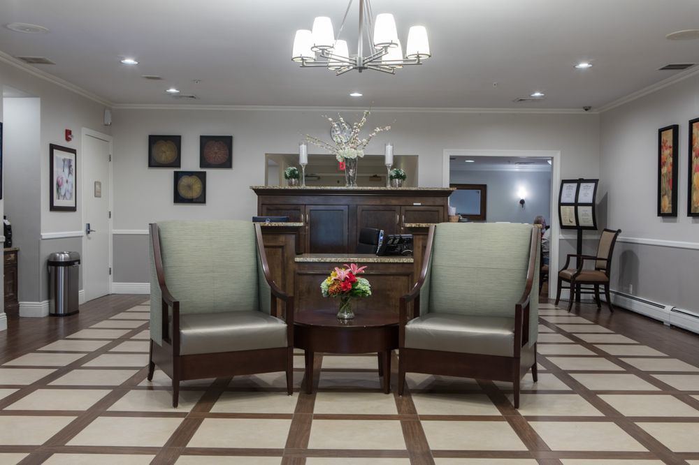 A cozy living room with two armchairs flanking a small table, adorned with a vase of flowers in front of a fireplace.