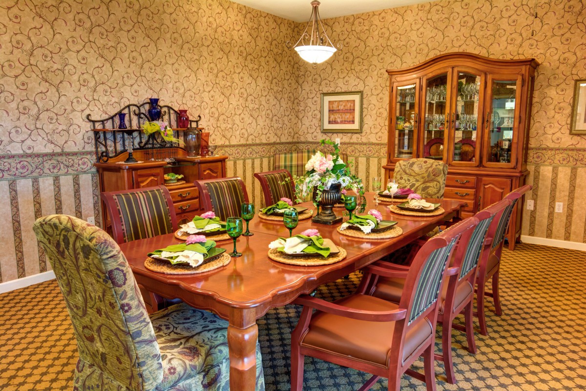 A classic dining room with a set table, featuring elegant decor and warm lighting.