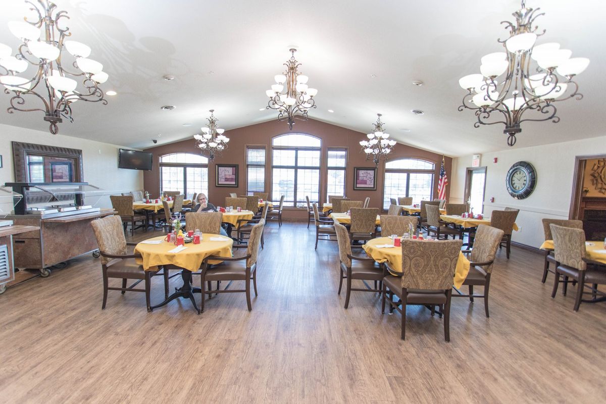 A spacious and well-lit dining area with elegantly set tables and comfortable chairs.