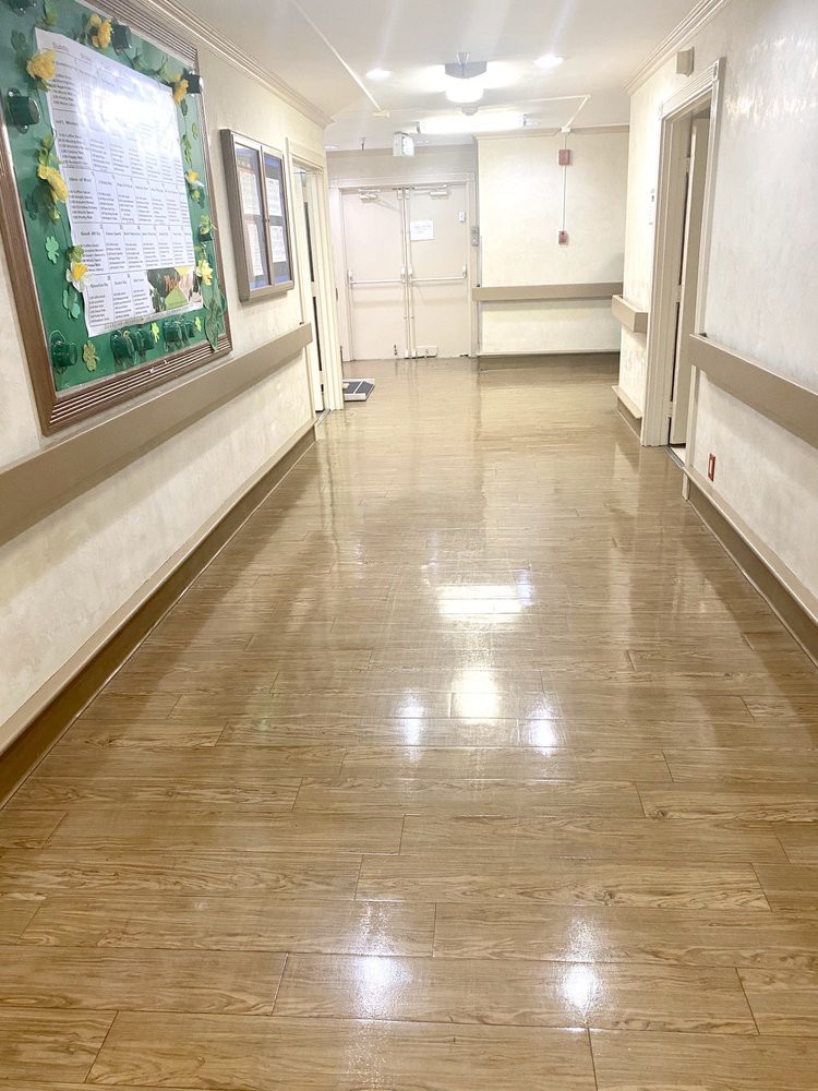 A clean and empty hospital hallway with polished floors and bright lighting.
