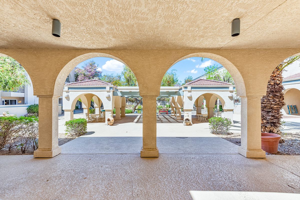 View through arched passageway to a landscaped courtyard.