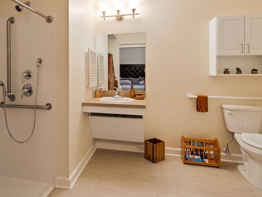 A modern bathroom with a shower, sink, and mirror, featuring neutral tones and minimalistic decor.