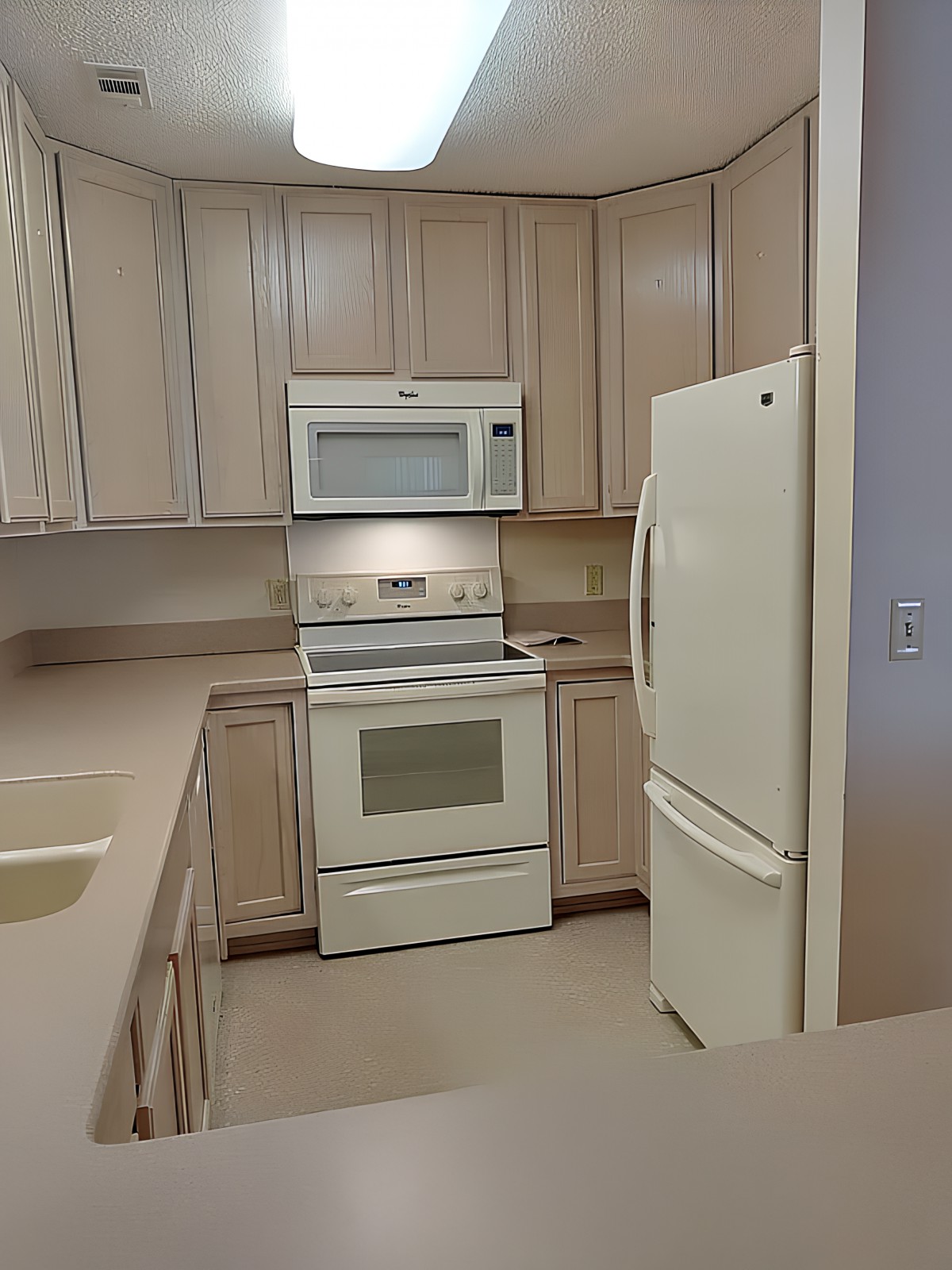 A modern kitchen with white appliances and wooden cabinets.
