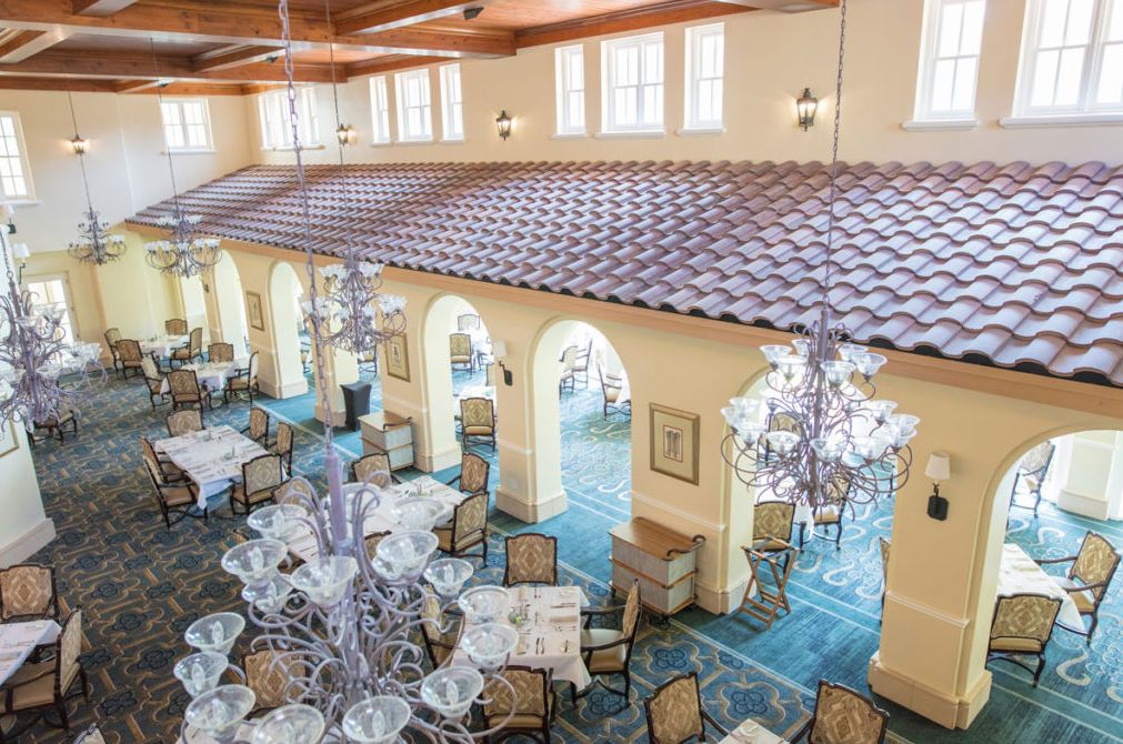 A spacious and elegantly decorated dining area with large chandeliers and a tiled roof interior.