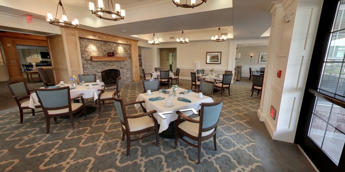 An elegant dining room with neatly arranged tables and a cozy fireplace.