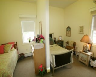 A shared bedroom with two beds separated by a partition, featuring various furniture and decor.