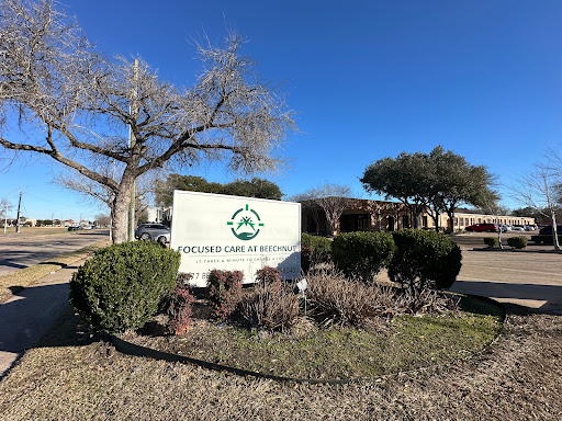A welcoming sign in front of a facility, surrounded by landscaping and under a clear blue sky.