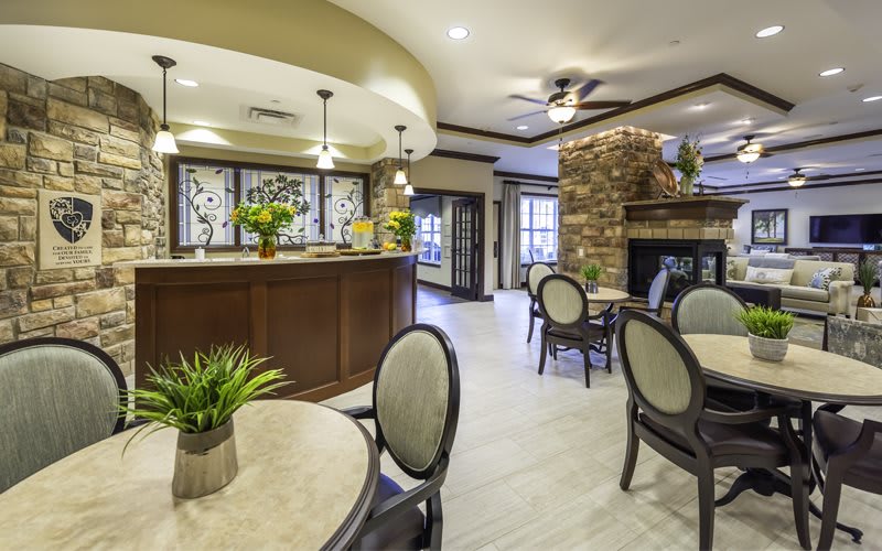 A stylish lounge area featuring modern seating, a kitchen counter, and a stone fireplace.