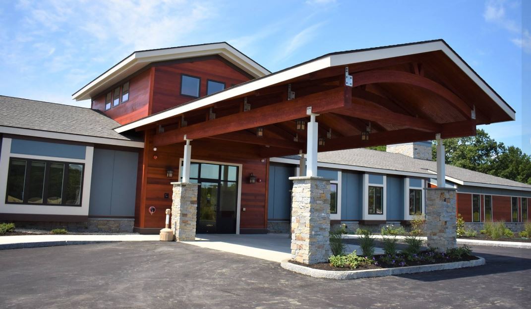 A modern building with a prominent entrance featuring stone pillars and a sloped roof.