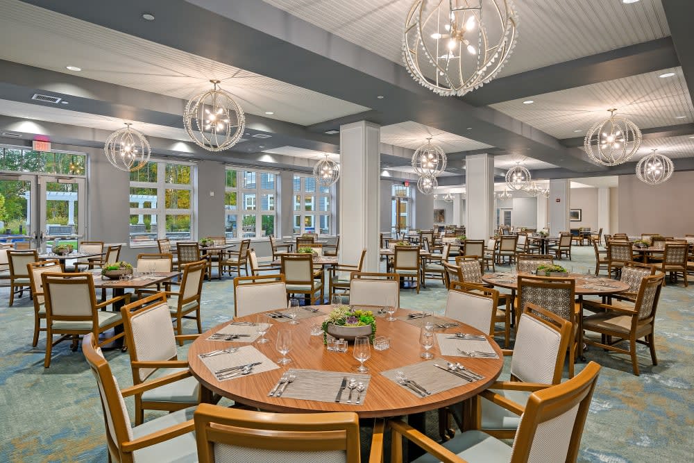 A spacious and modern dining room with elegantly arranged tables and chairs, featuring contemporary lighting fixtures.