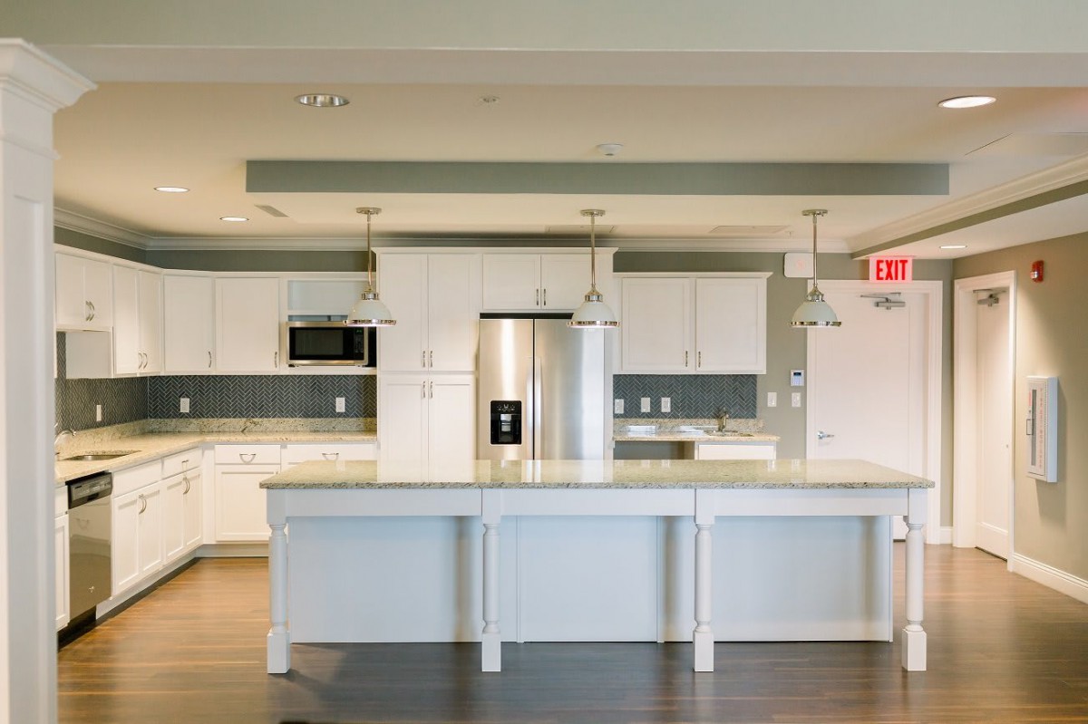 A modern kitchen with white cabinets, a large island counter, and stainless steel appliances.