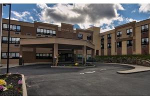 A hospital building with an entrance area and cloudy skies above.