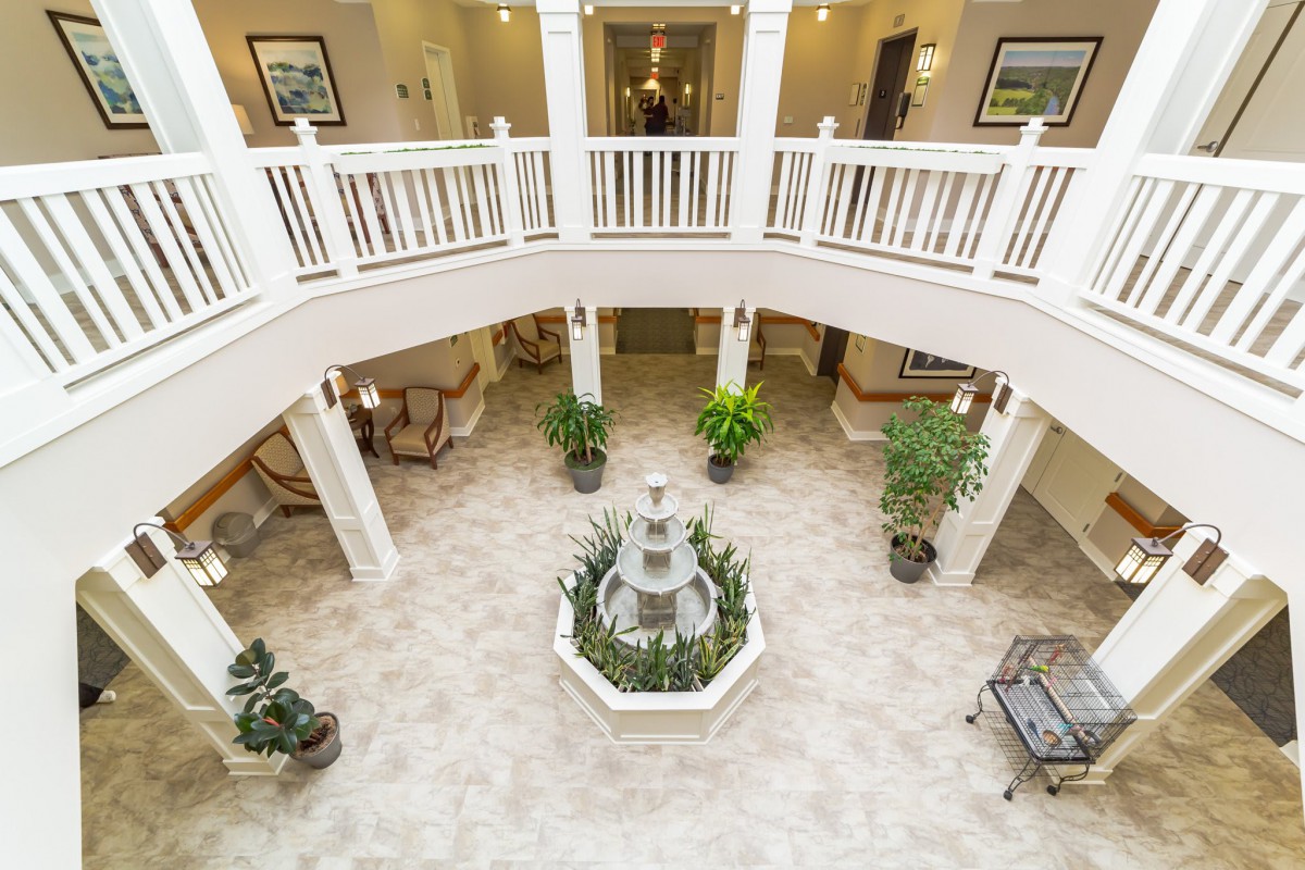 An elegant lobby with a central fountain, surrounded by plants and balcony railings.