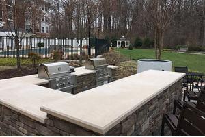 An outdoor kitchen area with grills and stone countertops in a backyard setting.