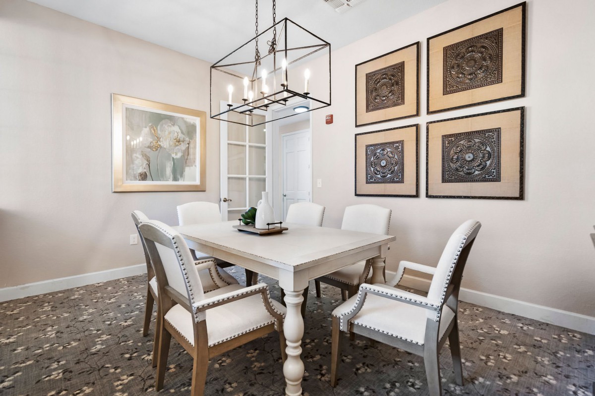 A beautifully designed dining room featuring a rectangular table surrounded by elegant chairs, adorned with contemporary artwork on the walls and an eye-catching lighting fixture overhead.