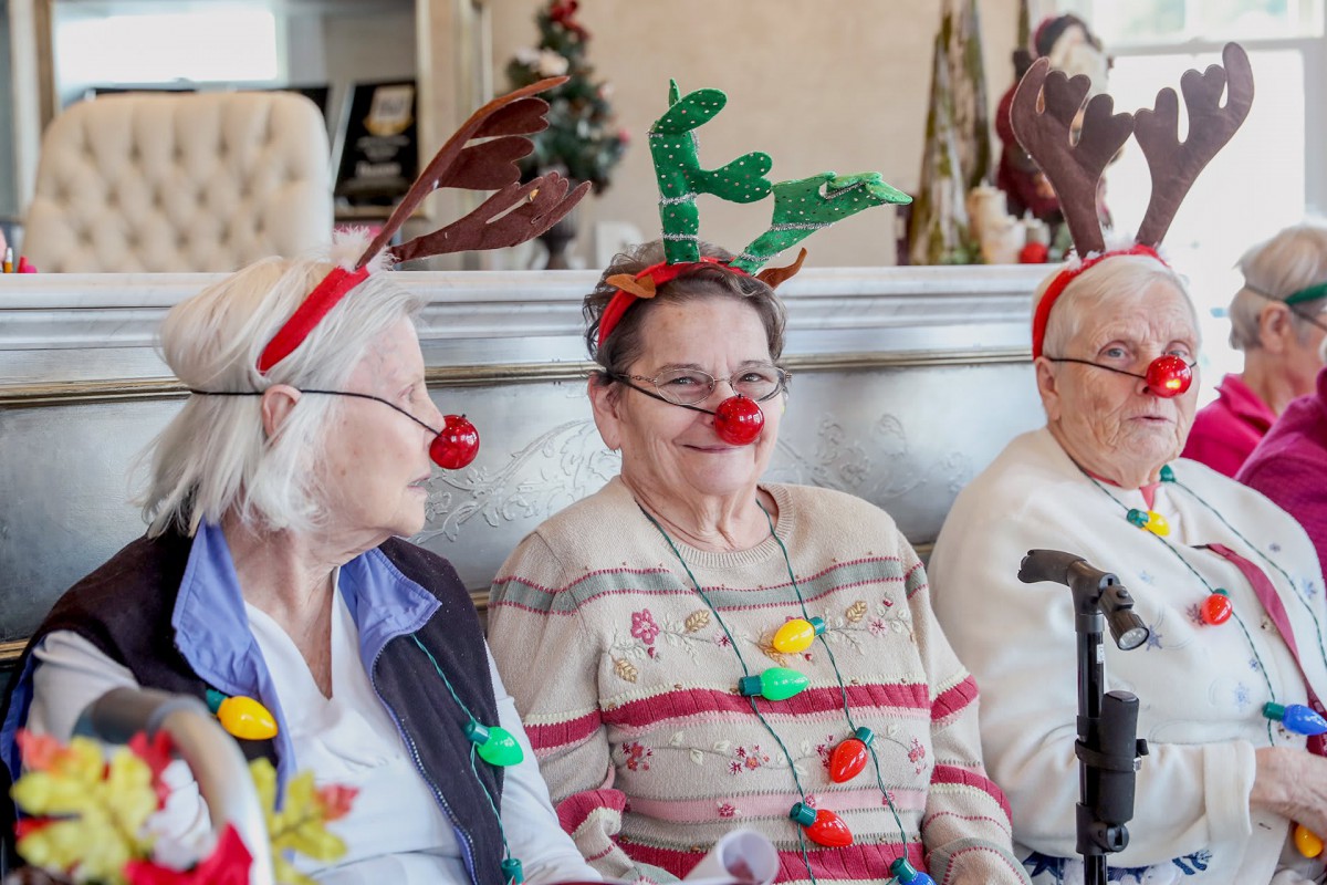 A group of seniors wearing festive reindeer headbands and red noses celebrate together.