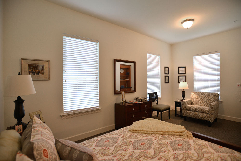 A cozy bedroom with a bed, chairs, and warm lighting.