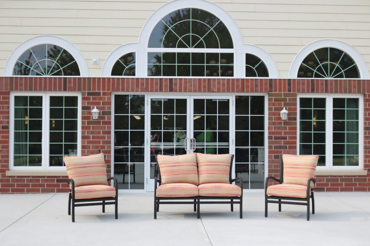 Outdoor patio furniture set against a brick wall with large arched windows.