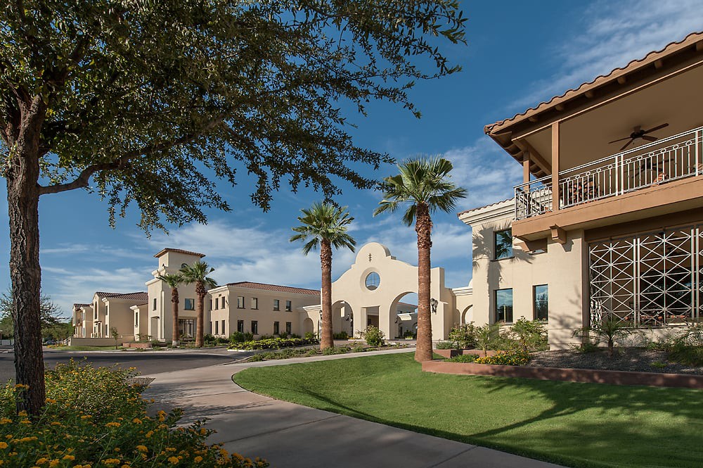 A scenic view of Spanish-style architecture with palm trees and a clear blue sky.