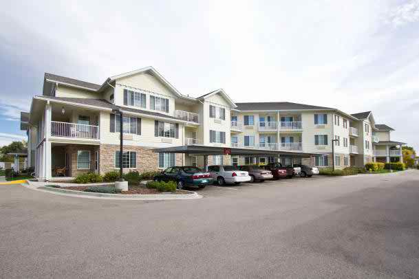A multi-story residential apartment building with a parking lot in front.