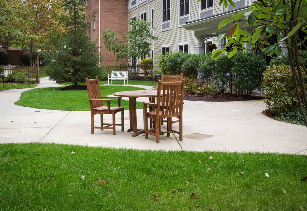 Wooden chairs and a table set in a serene garden patio.