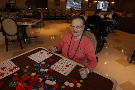 An elderly woman enjoying a game of bingo, surrounded by colorful markers and engaged in a social activity.