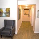 A modern hallway with a comfortable chair and decorative paintings on the walls.