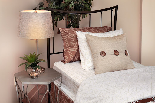 A cozy and stylish bedroom setup featuring decorative pillows, a modern lamp, and a small plant.