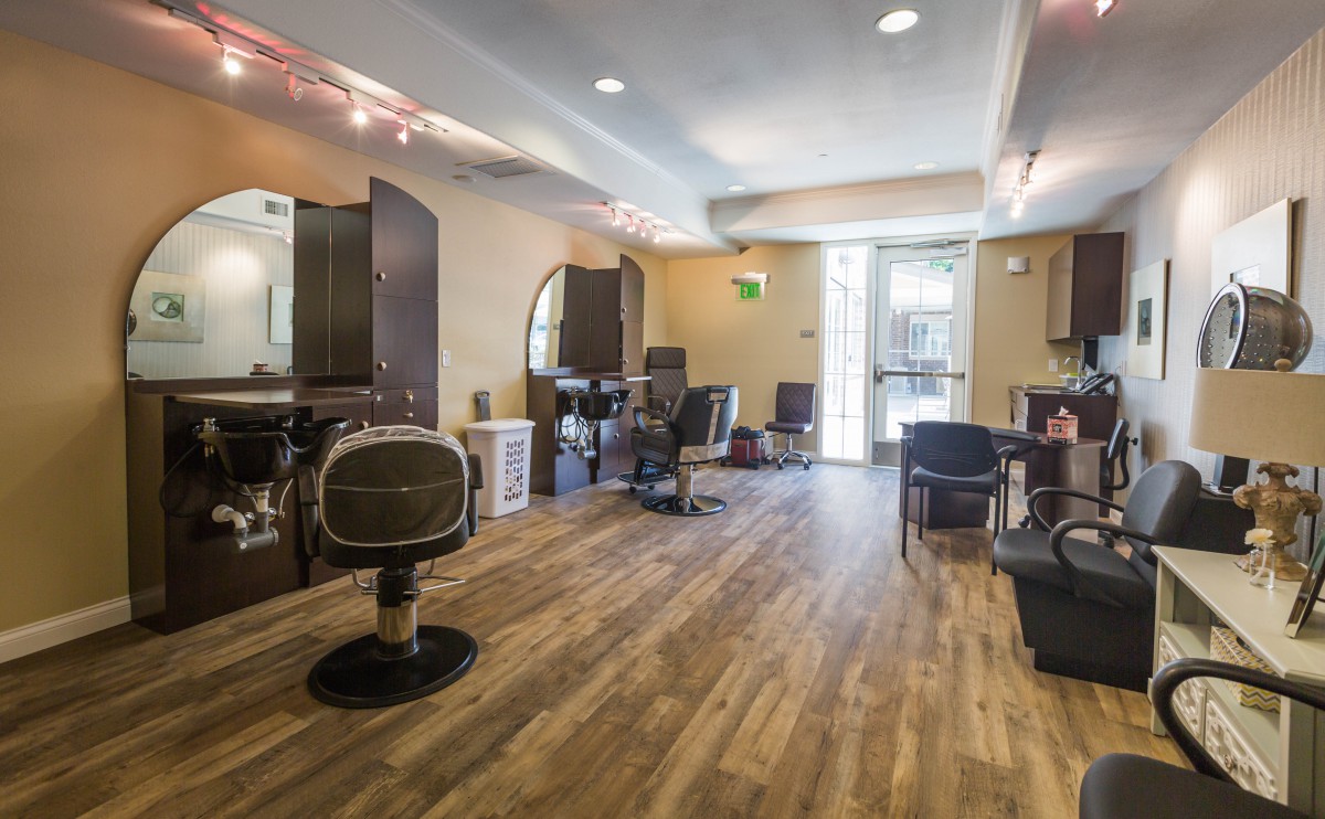 An empty hair salon with chairs and mirrors, featuring a wooden floor.