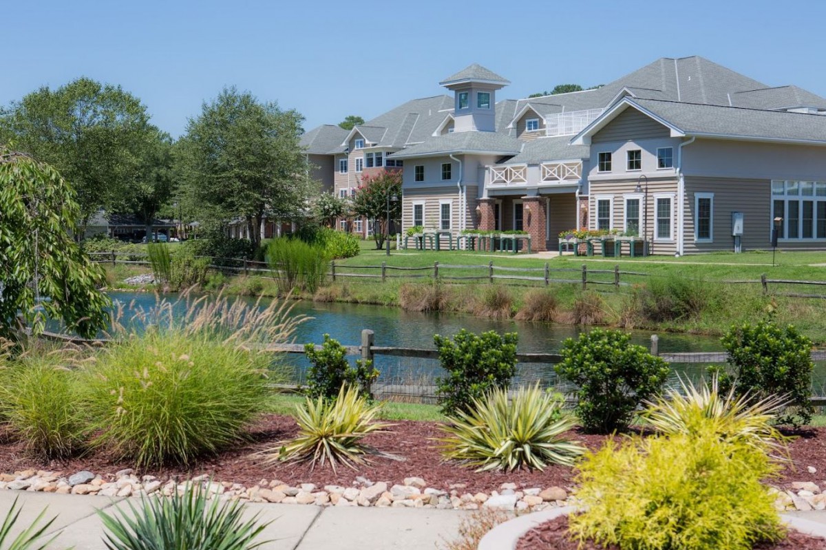 A scenic view of a residential area featuring well-maintained landscaping and a tranquil lake.