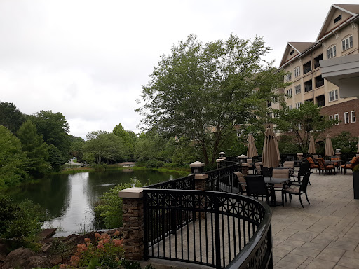 A serene lakeside view featuring lush greenery and outdoor seating.