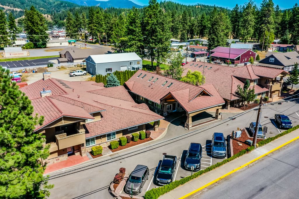 Aerial view of a residential area with buildings, cars parked along the street, and trees in the background.