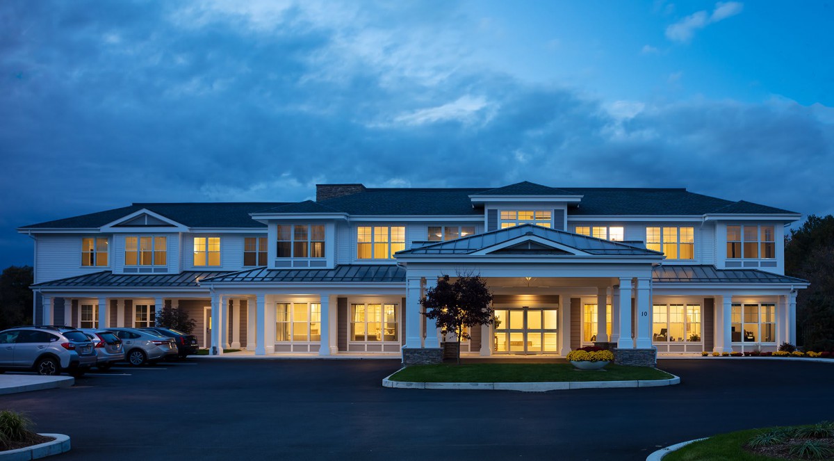 A well-lit hotel building stands against a cloudy evening sky.