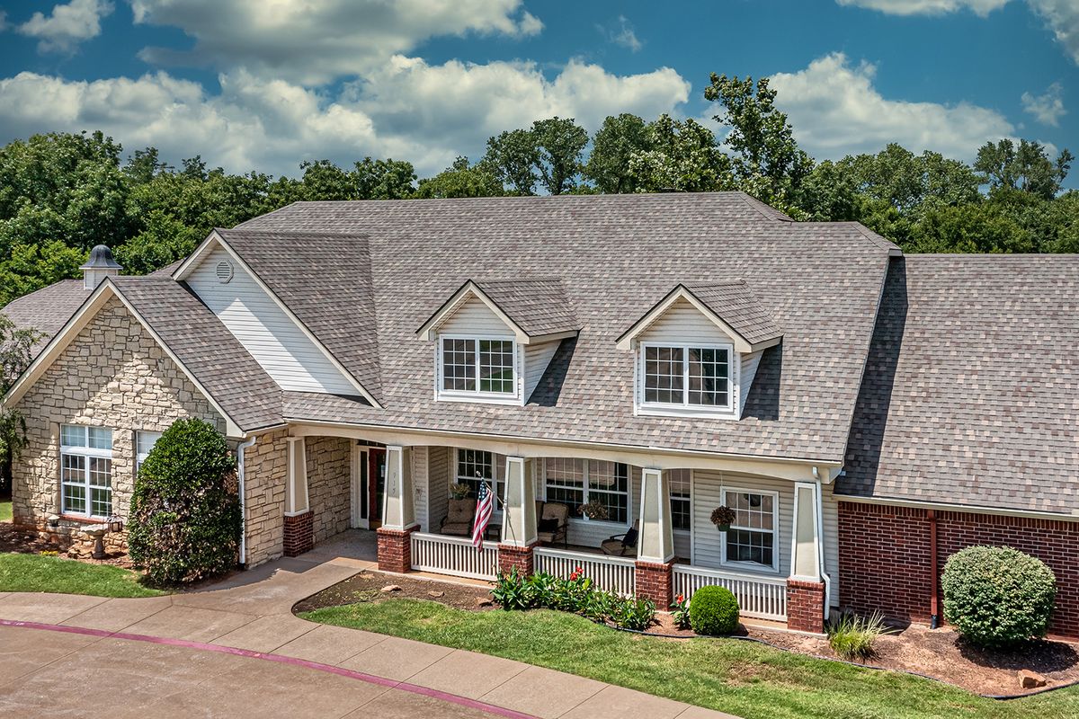 A suburban house with a large front porch and gabled roof on a sunny day.
