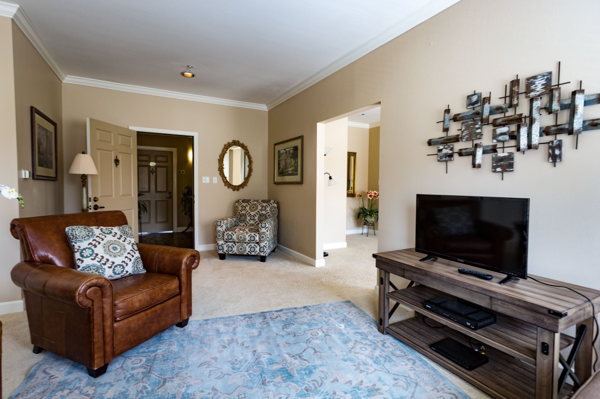 A cozy living room with a leather armchair, patterned chair, television, and decorative elements.