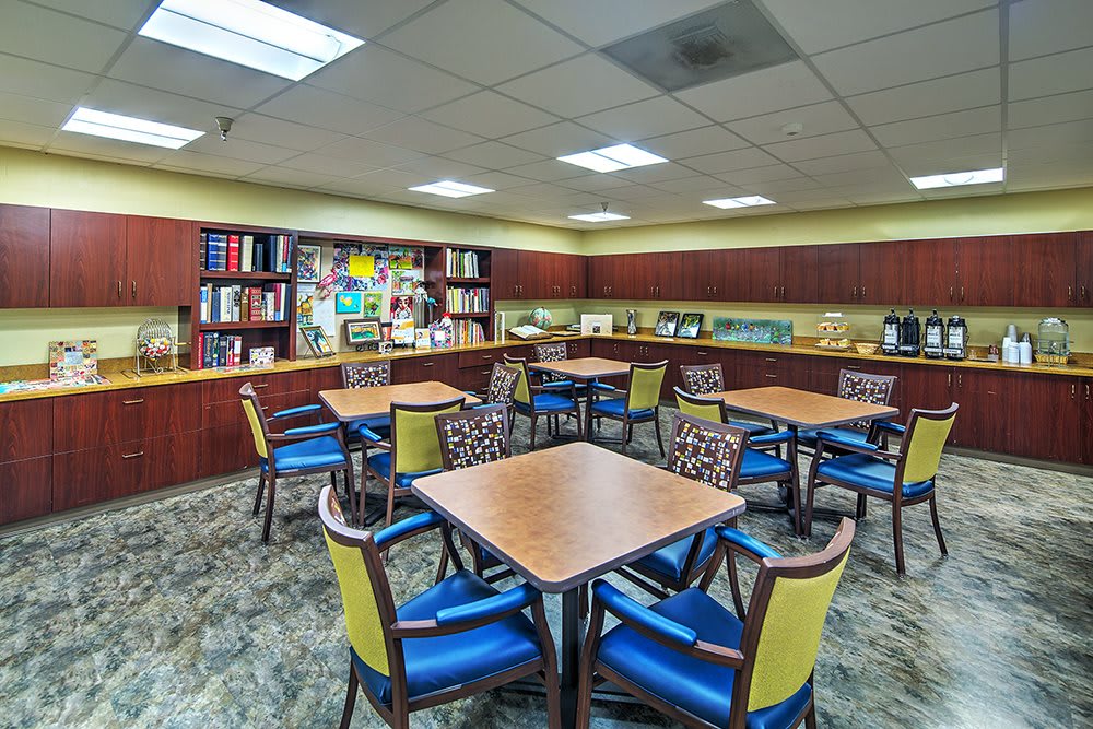 A cozy library reading room with tables, chairs, and bookshelves.