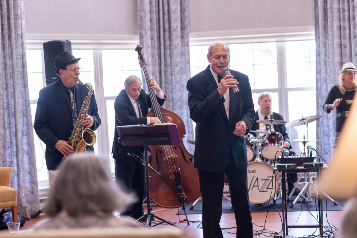 A jazz band performing with musicians playing the saxophone, double bass, and drums, accompanied by a vocalist.