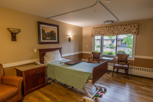 A well-appointed patient room in a healthcare facility, featuring a hospital bed and comfortable seating by the window.