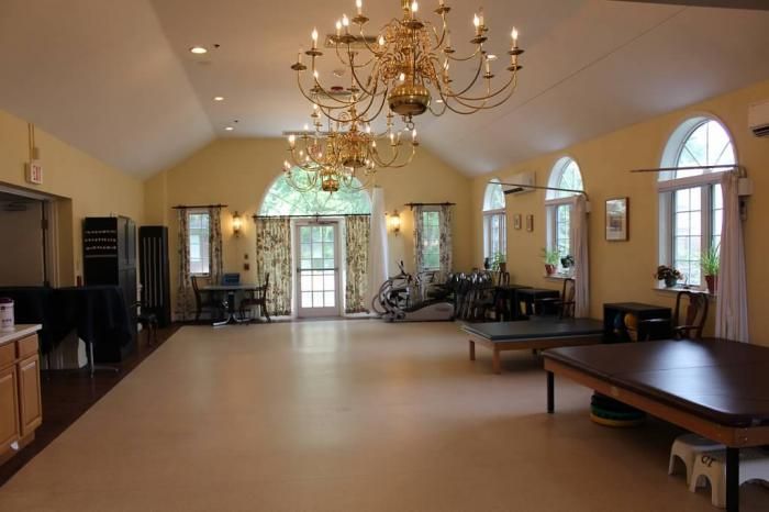 An elegant hall with chandeliers and large windows, featuring classic furniture.
