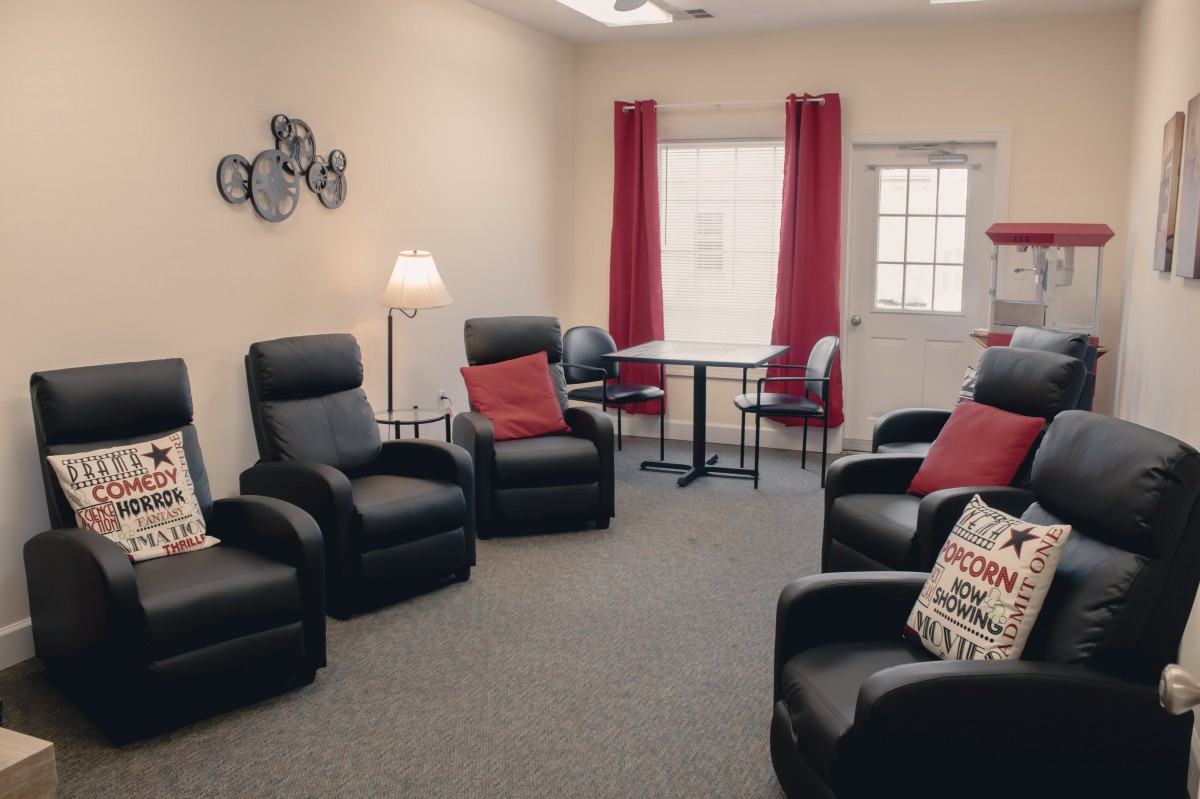 A cozy living room with black armchairs, red curtains, and decorative pillows.