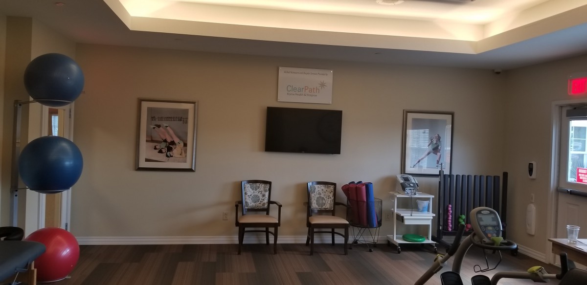 A waiting room area with chairs, a television, and framed artwork on the walls.
