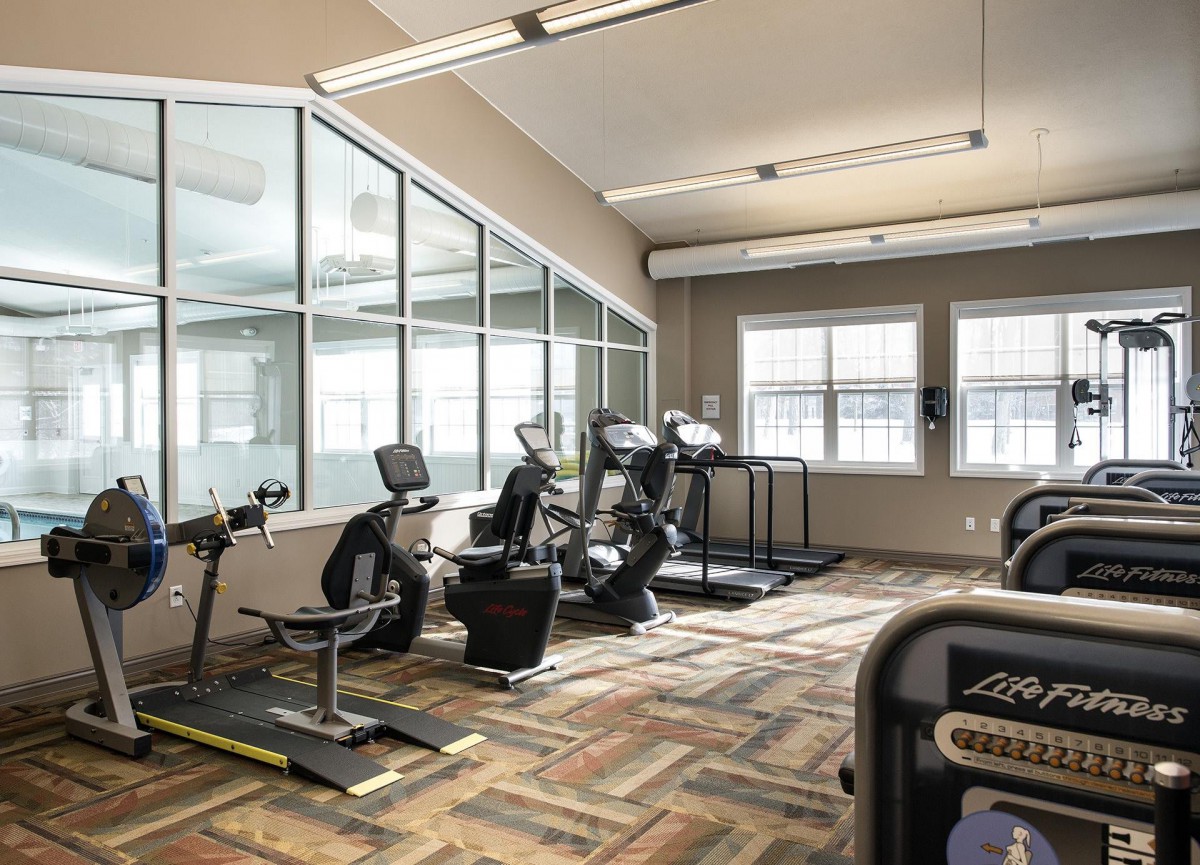 A well-lit gym featuring treadmills and stationary bikes.