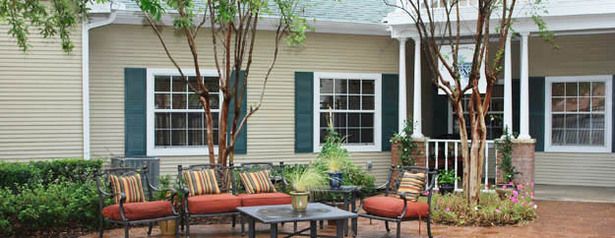 A cozy patio area with outdoor seating in front of a house with green shutters.