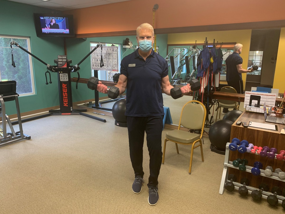 A person wearing a mask is jumping rope in a gym.