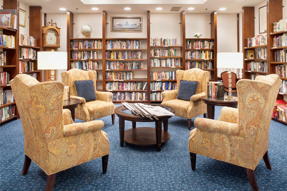 A cozy library reading area with armchairs and bookshelves filled with books.