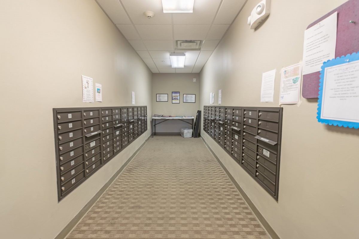 A hallway lined with mailboxes in an indoor mailroom.