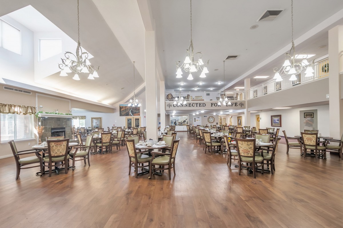 A spacious and elegantly designed dining hall with numerous tables and chandeliers.