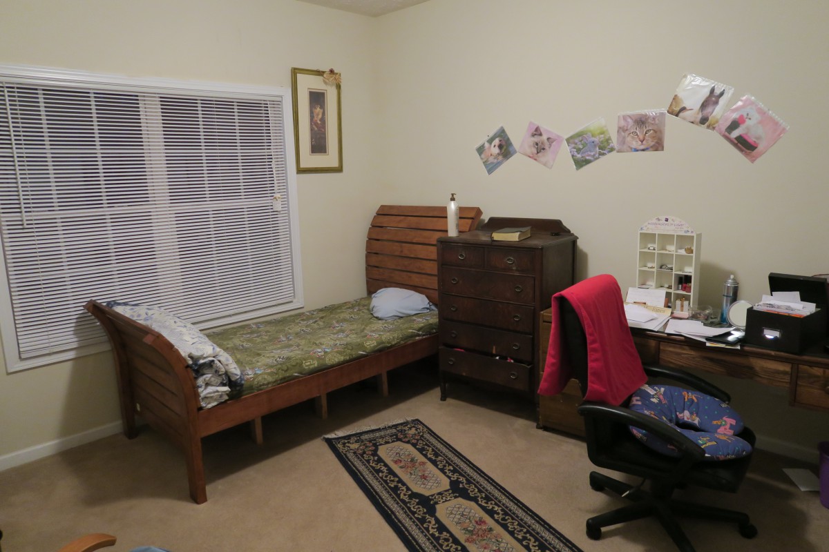 A neat and tidy bedroom with a single bed, a desk, and decorative wall items.